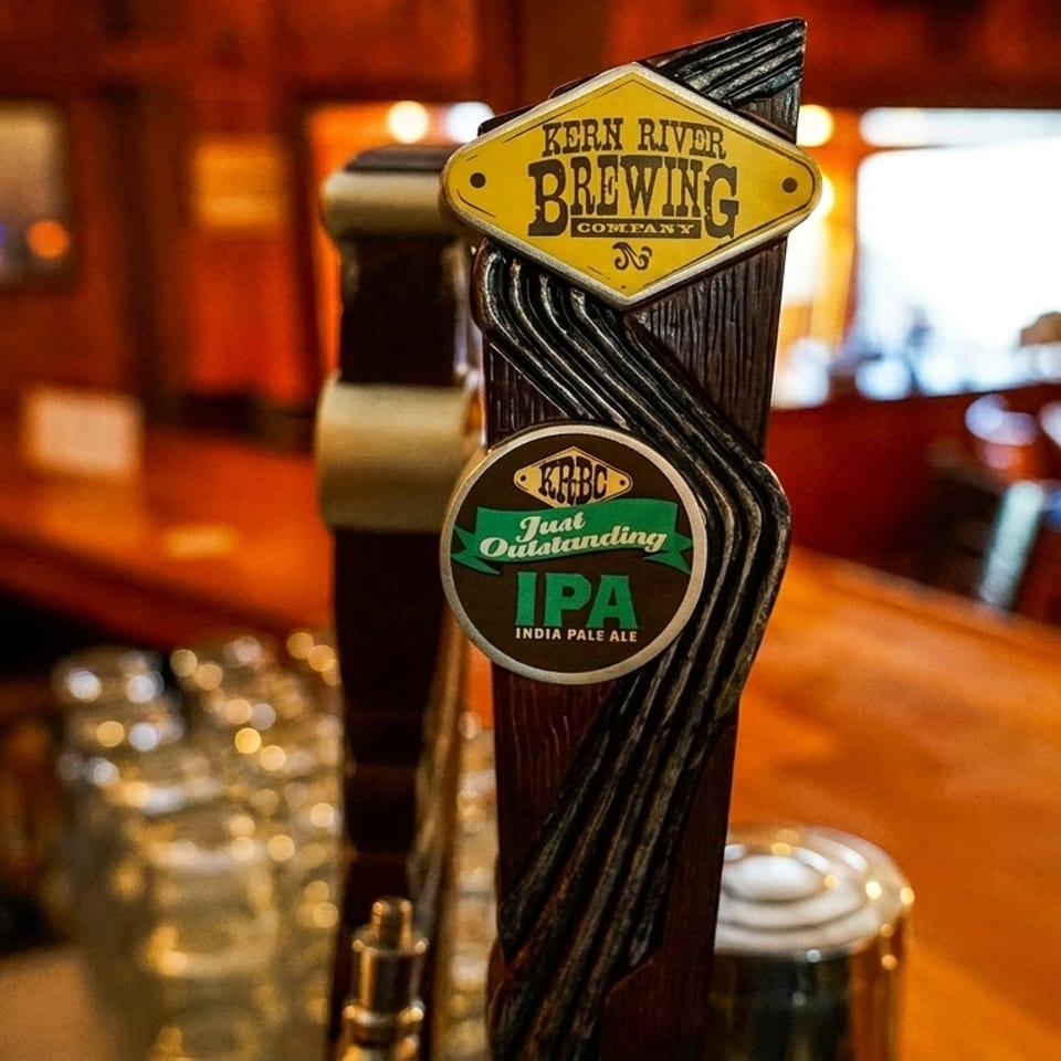Close-up of a Kern River Brewing Company beer tap handle in a dimly lit bar.
